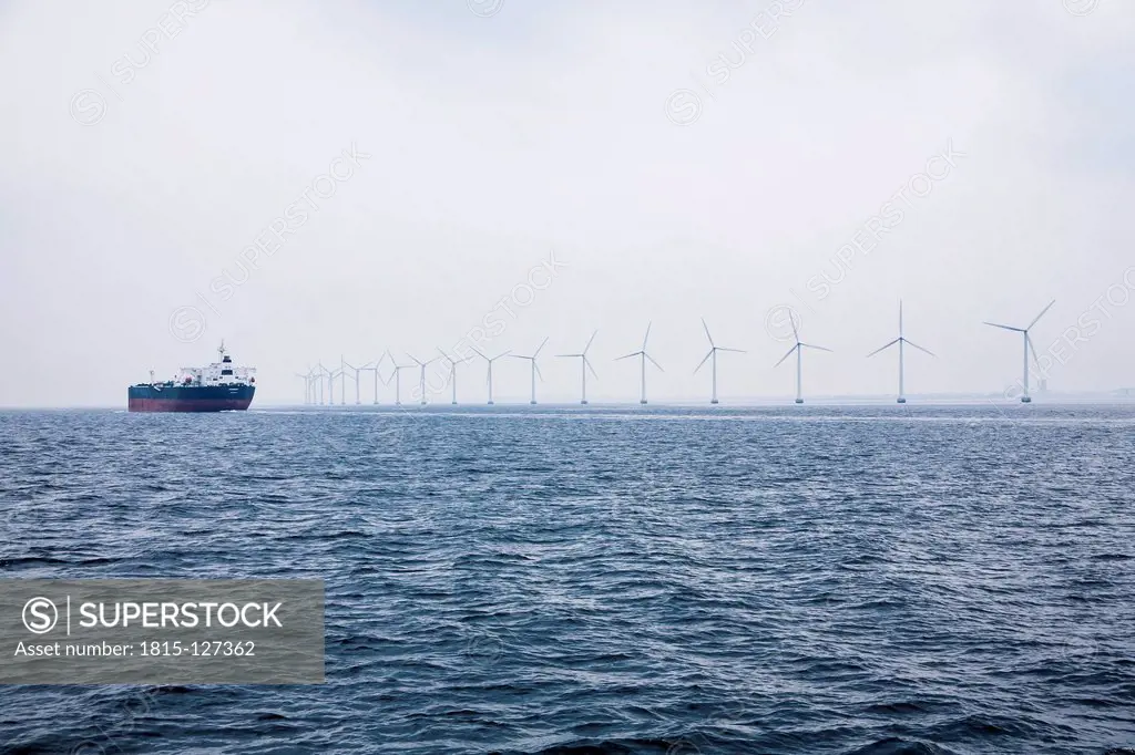 Germany, Hamburg, View of cargo ship in front of the wind-wheels of an offshore windpark