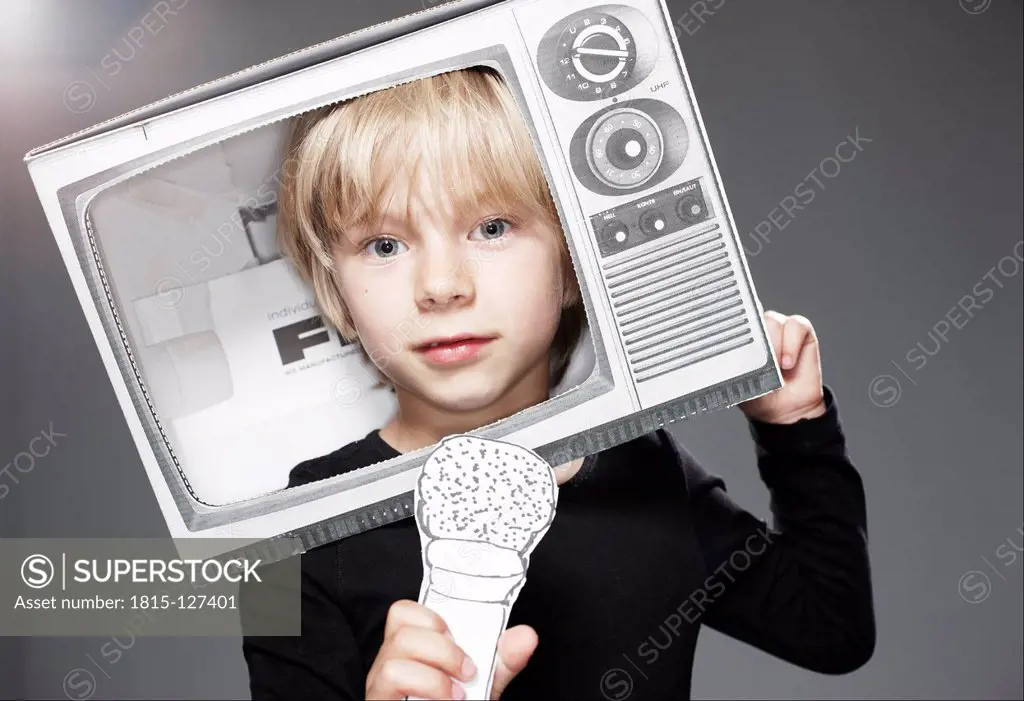 Portrait of boy head in paper TV with paper microphone against grey background