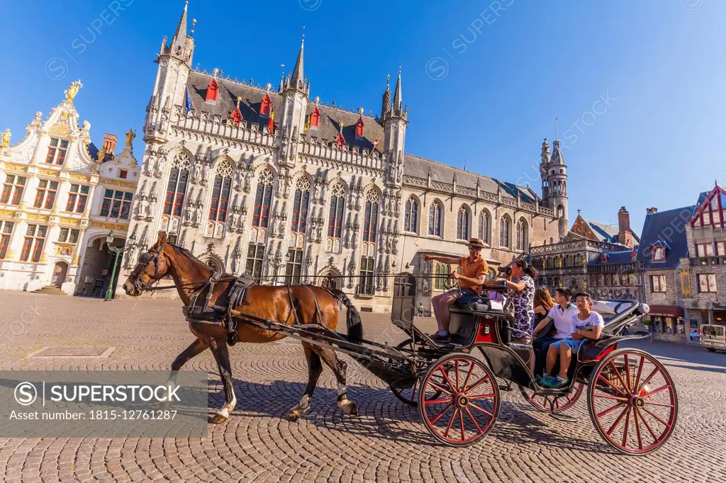 Belgium, Bruges, Tourists in horse cab in fornt of town hall on castle square