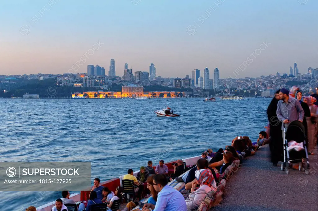 Turkey, Istanbul, People sitting in cafe in Bosphorus, Dolmabahce Palace and Sisli in background