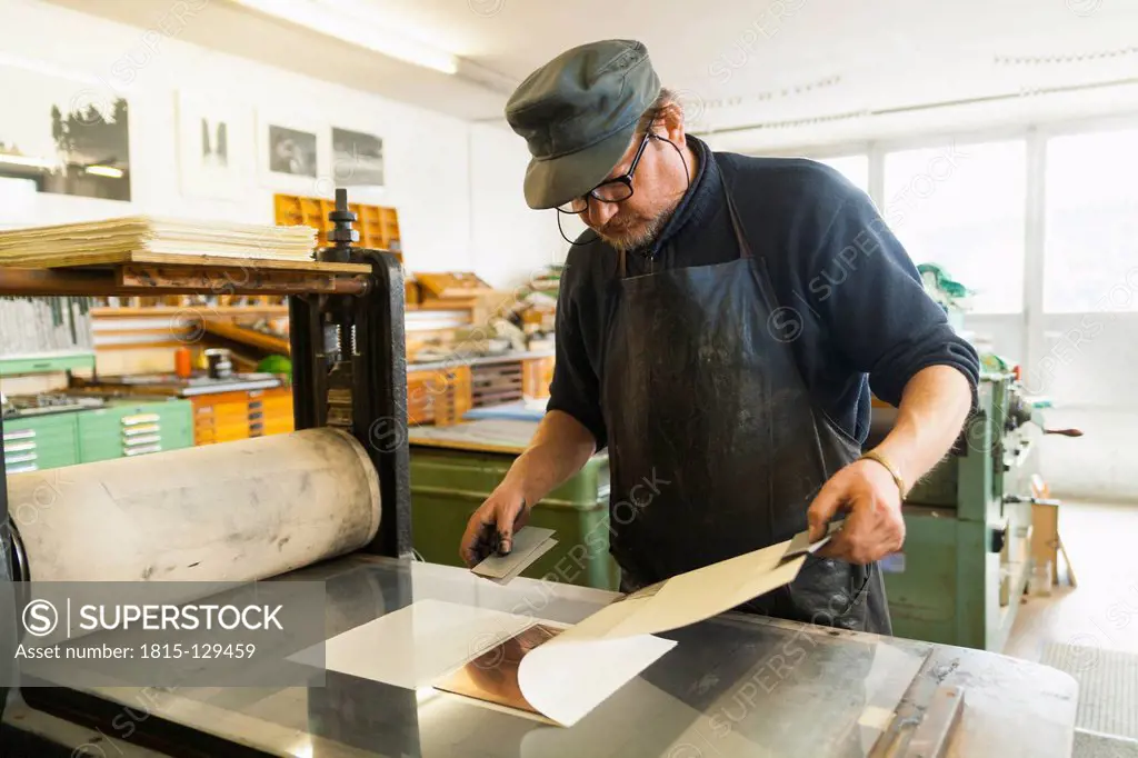 Germany, Bavaria, Mature man looking at deckle edge paper in print shop