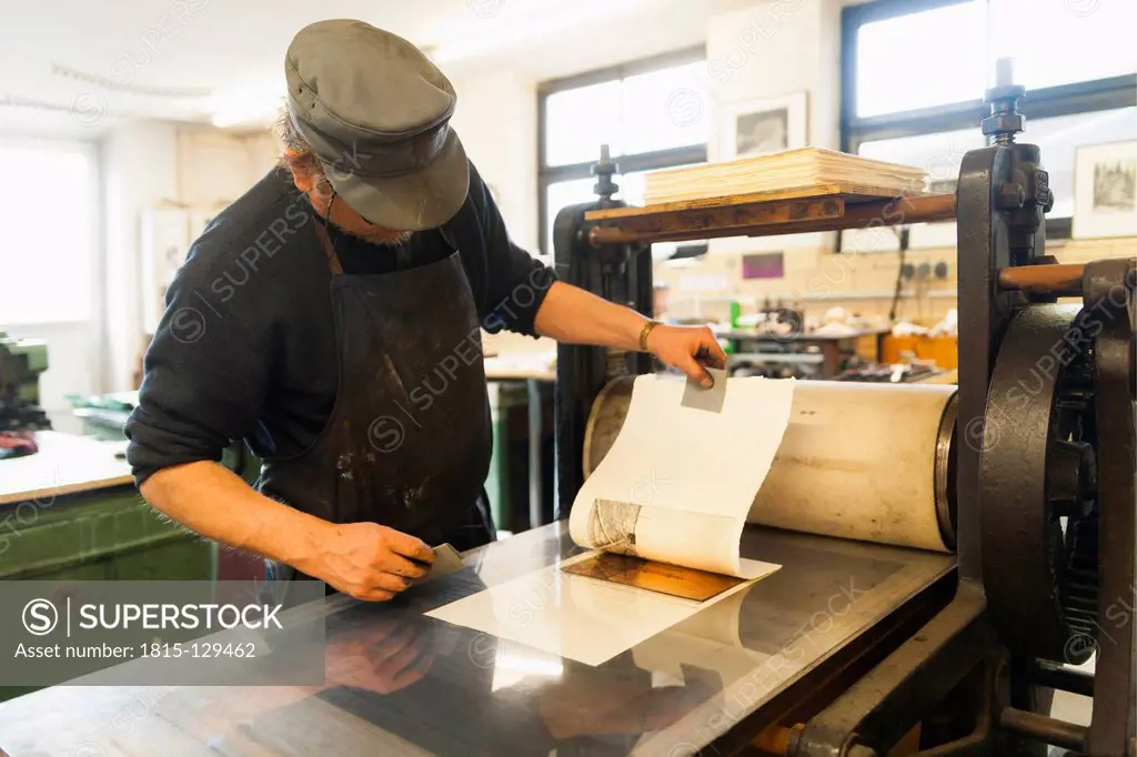 Germany, Bavaria, Mature man looking at deckle edge paper in print shop