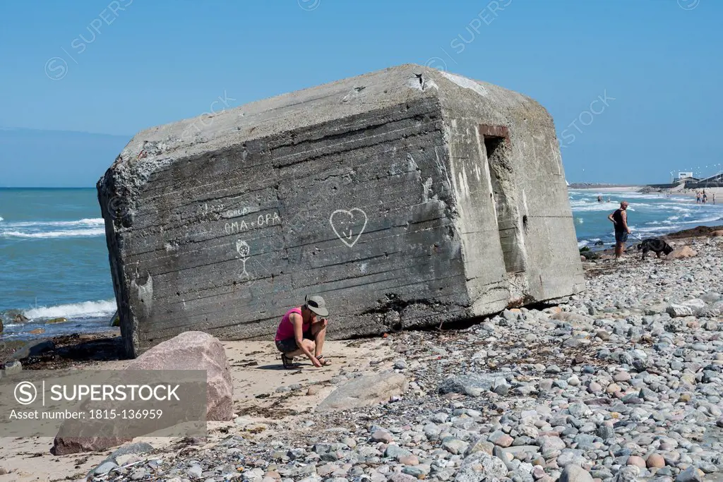 Denmark, View of mature woman collecting shells at Bunker ruin