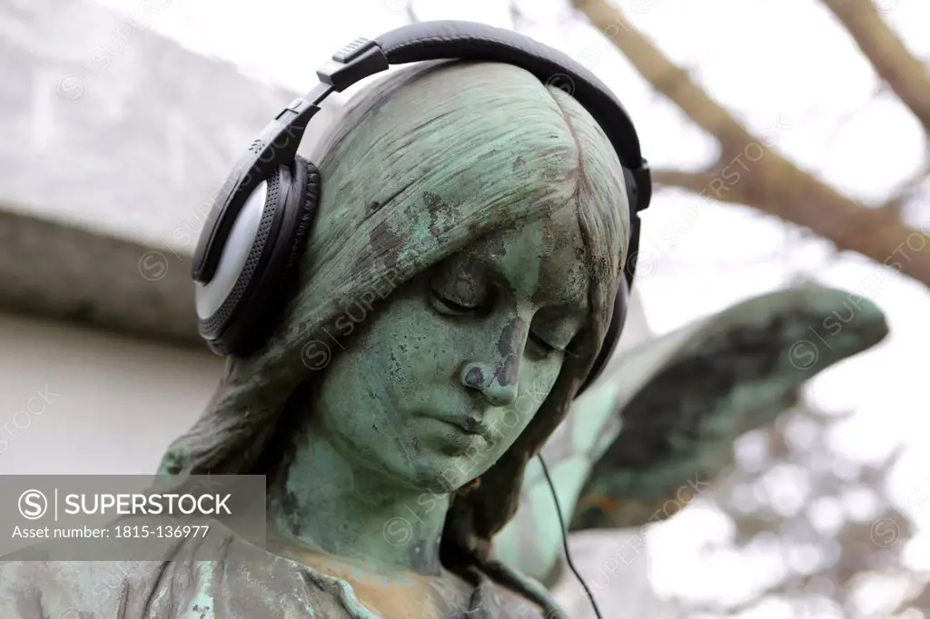 Germany, Cologne, Angel statue with headphones in cemetery