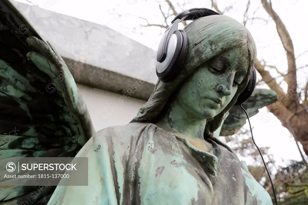 Germany, Cologne, Angel statue with headphones in cemetery