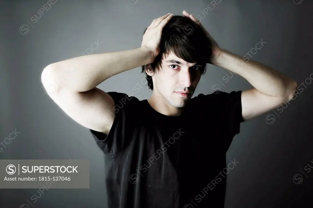 Portrait of young man against grey background, close up