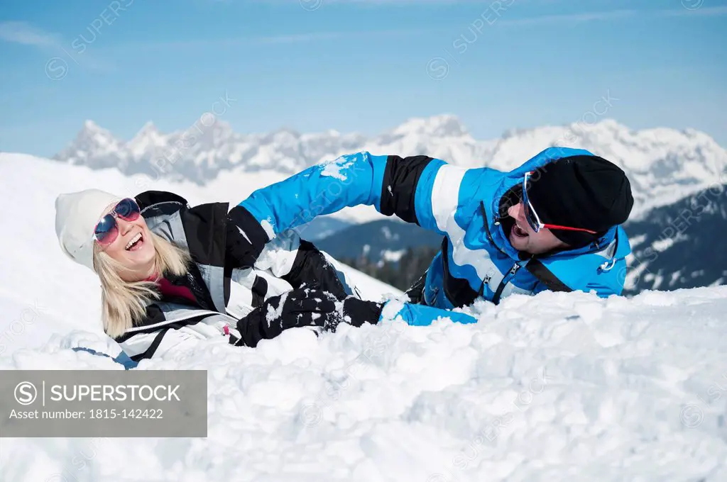 Austria, Salzburg, Young man and woman having fun in snow, smiling