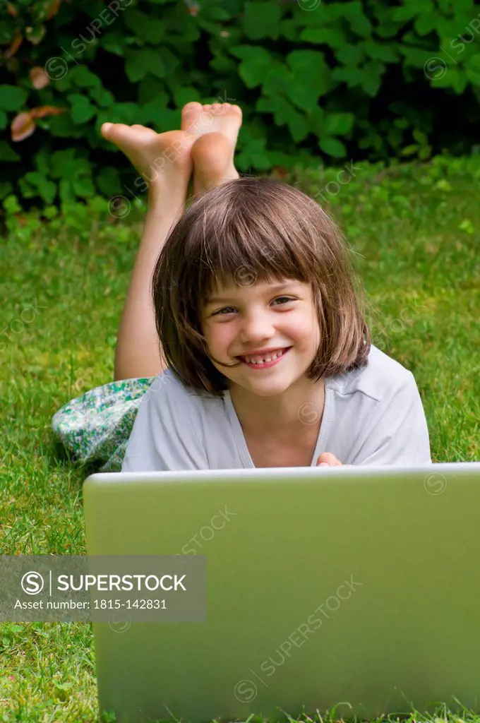 Germany, Rhineland Palatinate, Kaiserslautern, Portrait of girl with laptop in garden, smiling