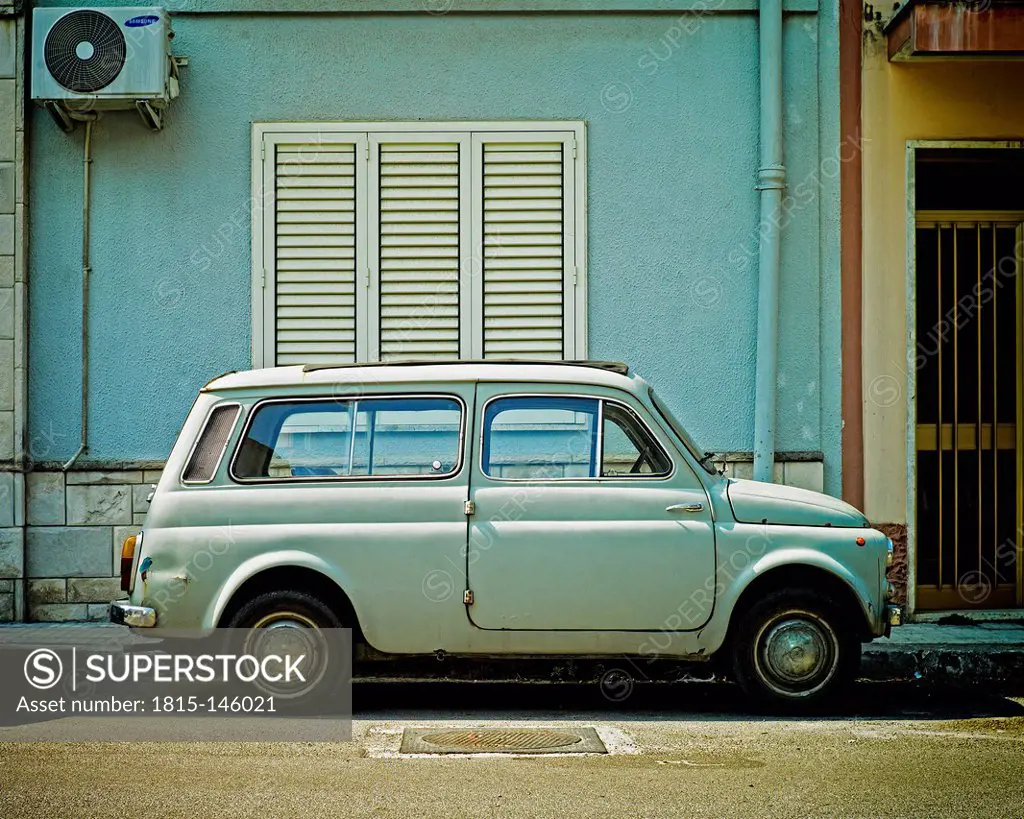 Italy, Old blue fiat 500 in front of blue wall