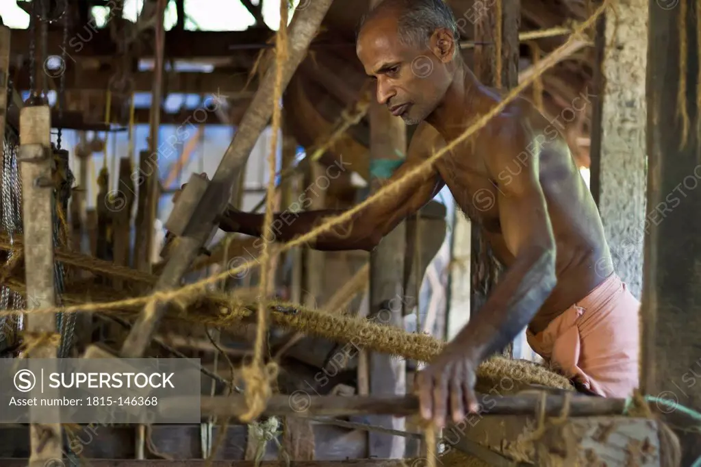 India, Kerala, Kochi, Man working at coconut doormat factory