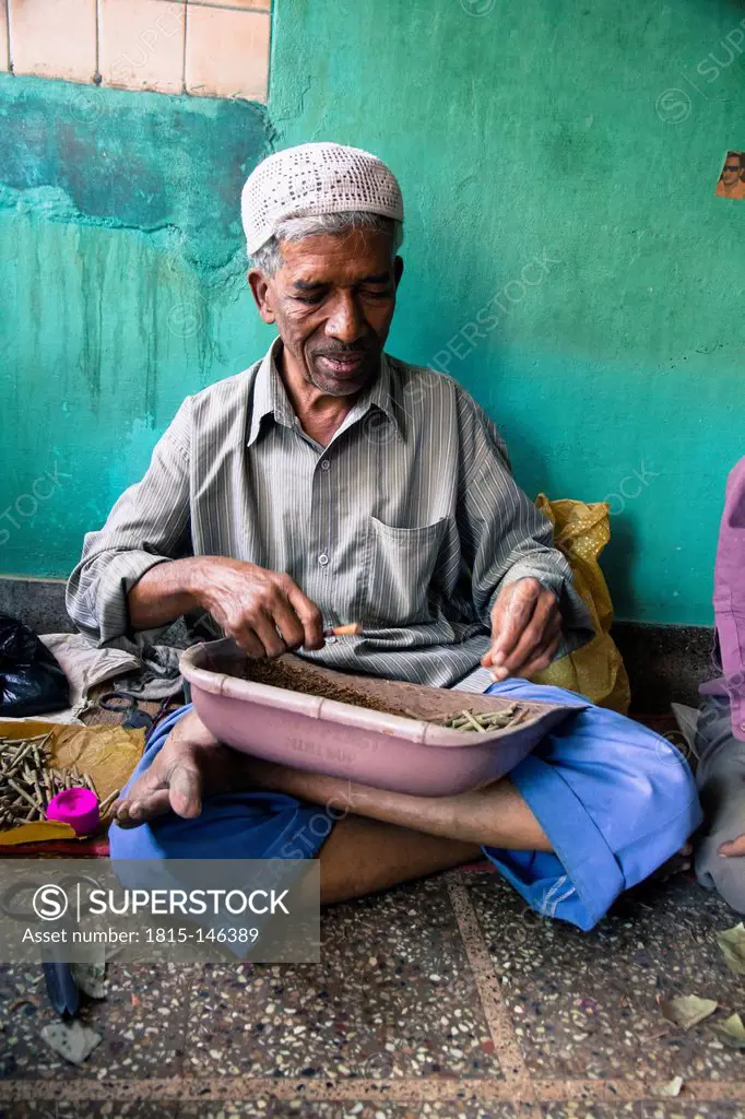 India, Mysore, Old man wrapping tobacco in beedi