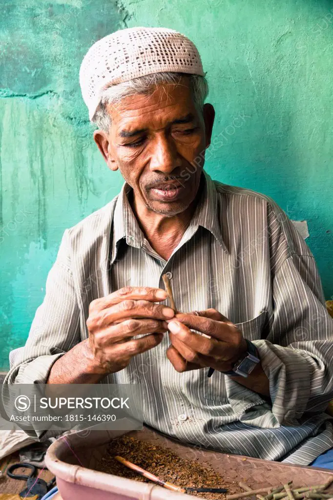 India, Mysore, Old man wrapping tobacco in beedi