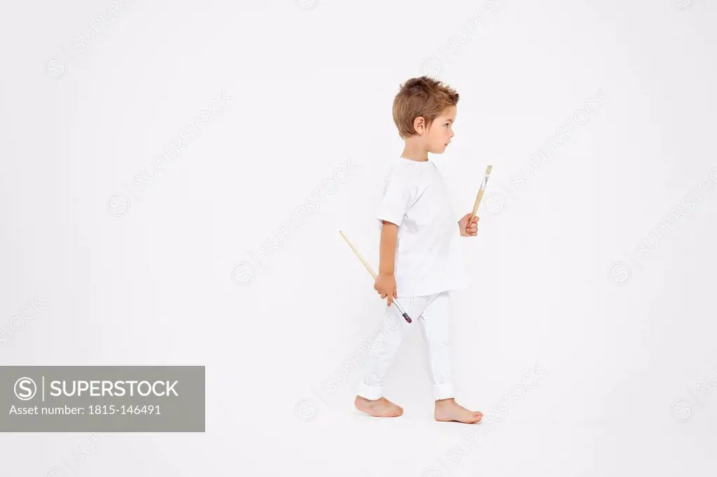 Toddler holding paint brushes