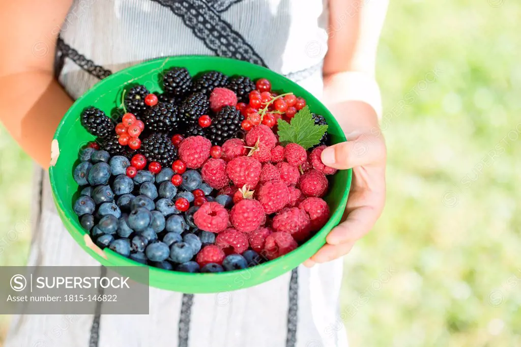 Germany, Bavaria, Girl holding bowl of berries