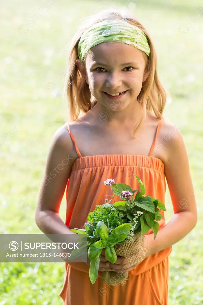 Germany, Bavaria, Portrait of girl holding bunch of herbs, smiling