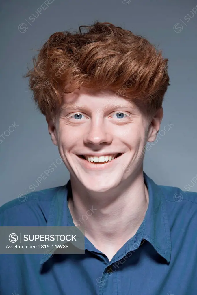 Portrait of young man against grey background, smiling