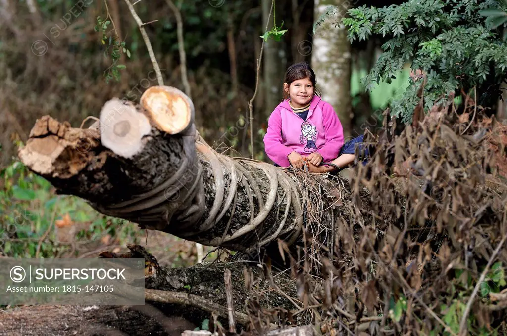 Paraguay, Caaguazu, Jaguary, Guarani girl sitting on tree trunk