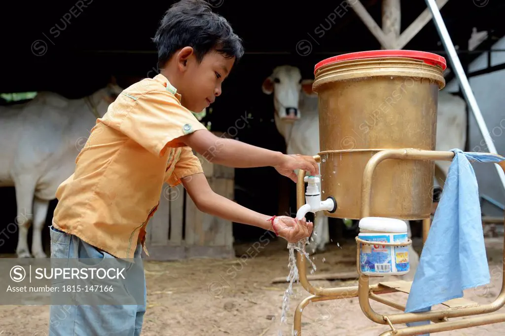 Cambodia, Takeo Province, Boy washing hands at water tank