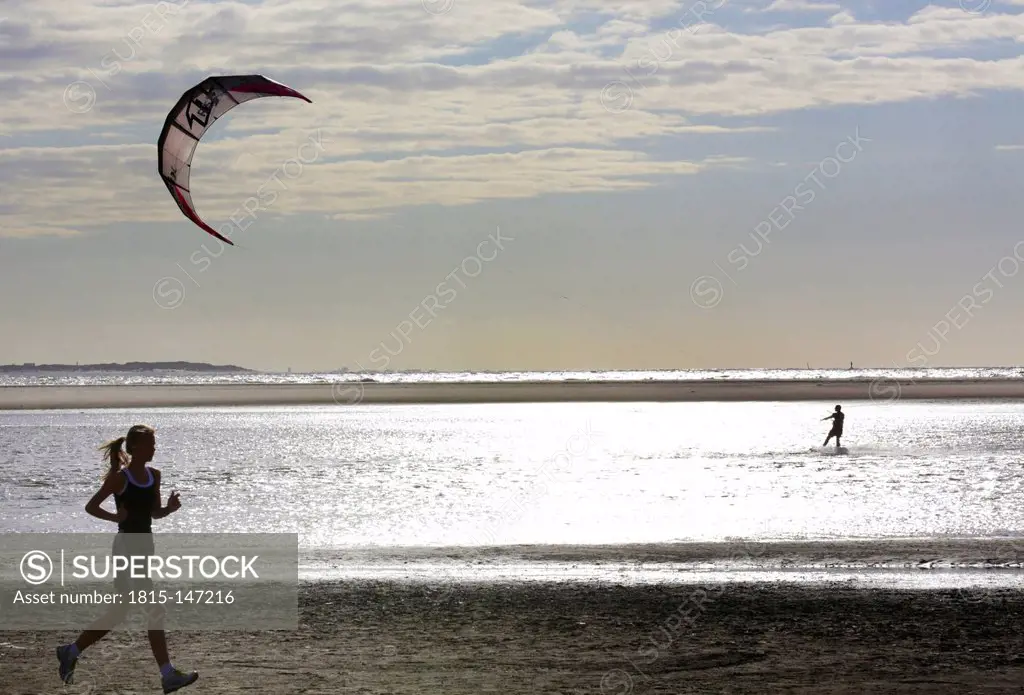 Germany, Lower Saxony, East Frisia, Langeoog, jogging and kiting at the beach