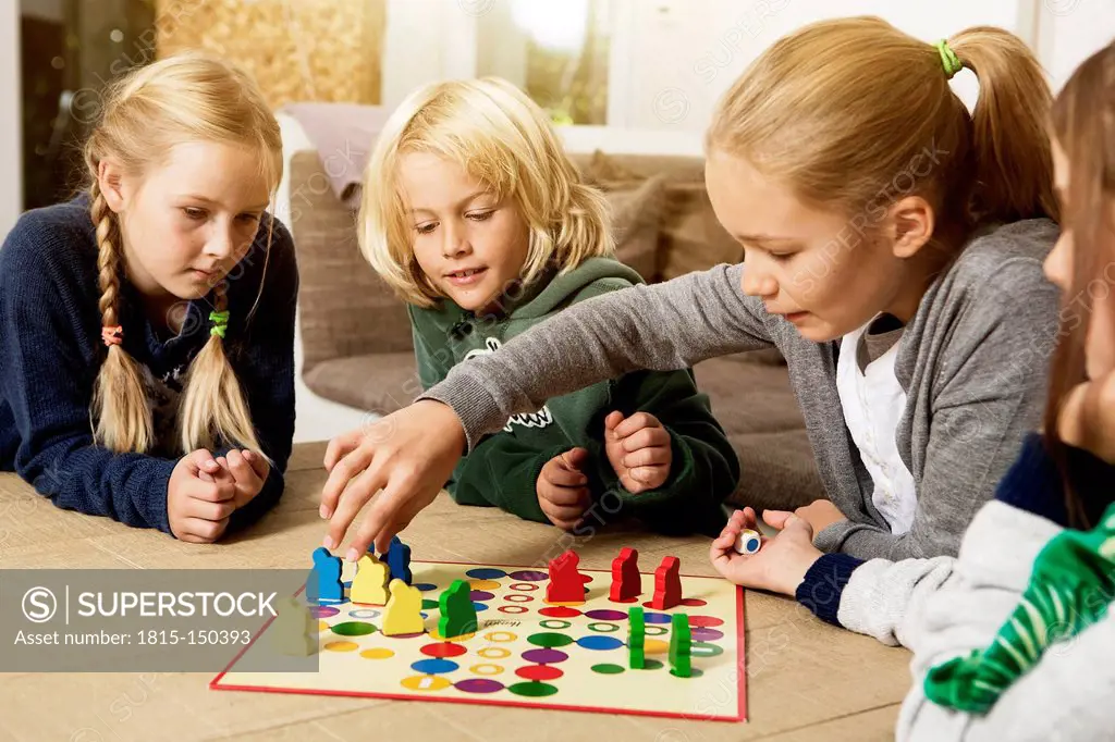 Four children playing ludo in living room