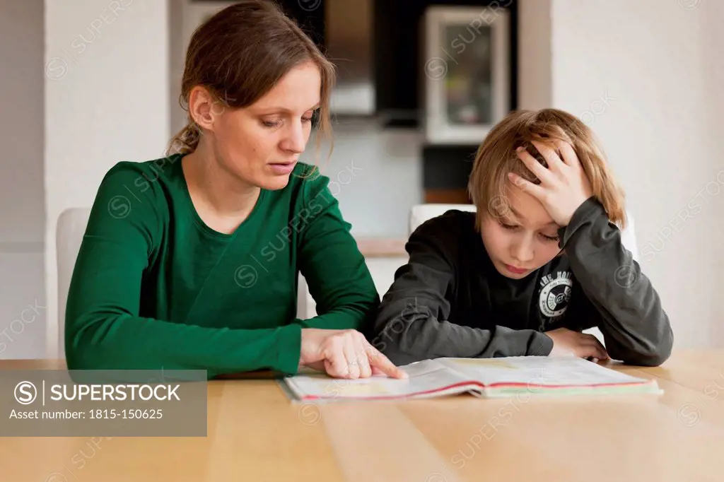 Germany, Rhineland-Palatinate, Neuwied, woman helping her son by doing his school work