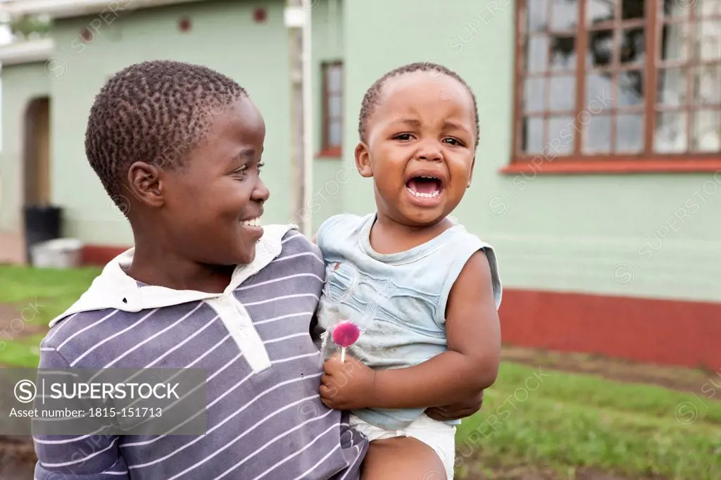 South Africa, KwaZulu-Natal, Eshowe, Boy holding crying baby