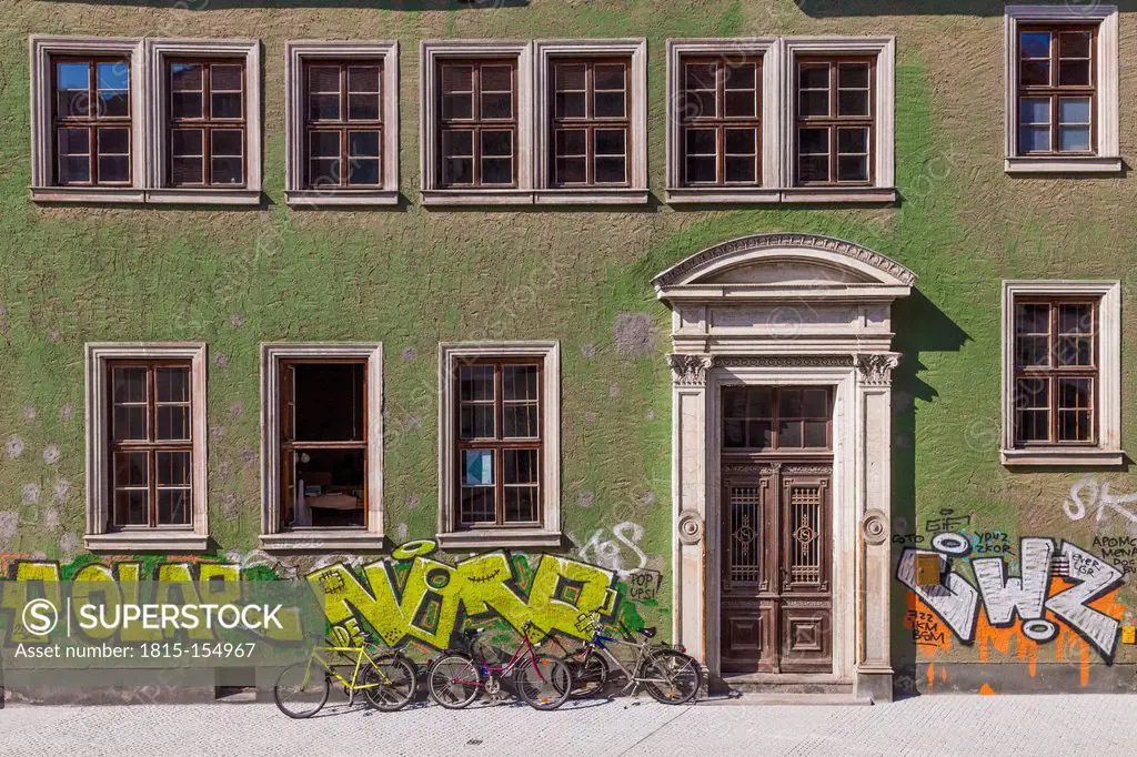 Germany, Saxony-Anhalt, Halle, House front with graffitis and bicycles