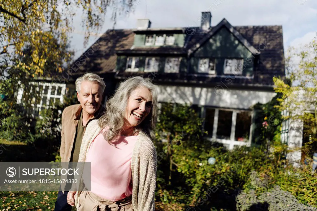 Happy senior couple in garden of their home in autumn