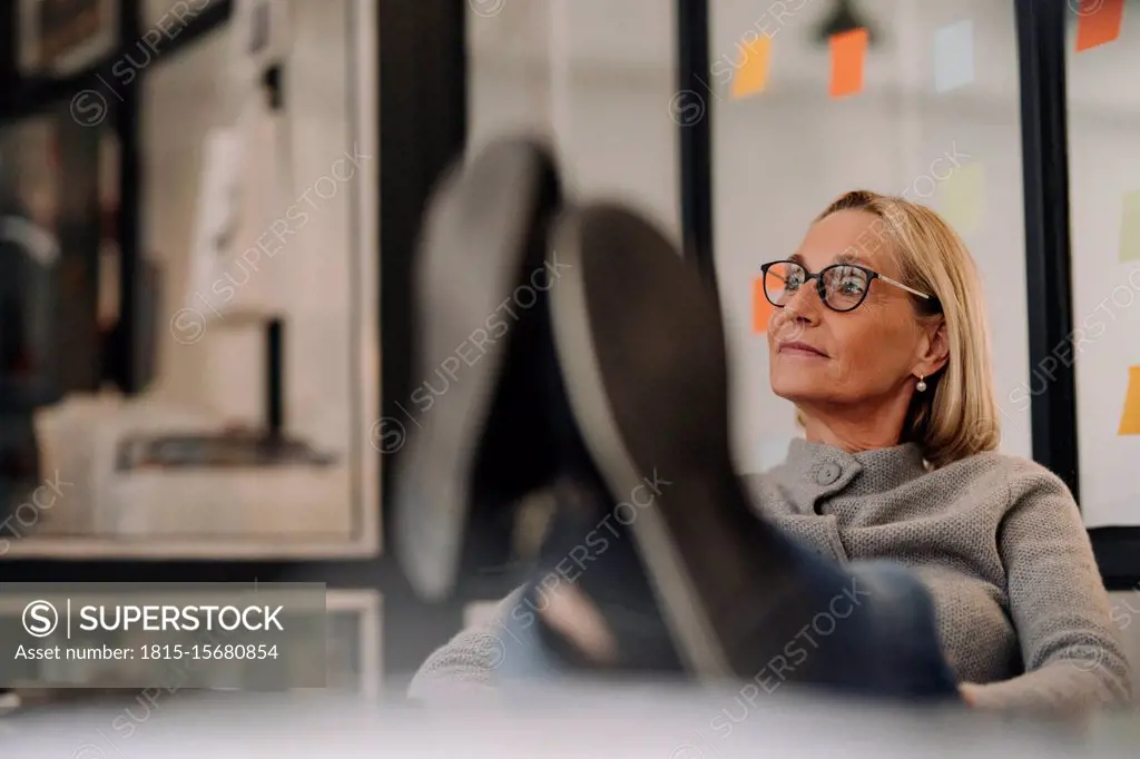 Mature businesswoman in office with feet on desk