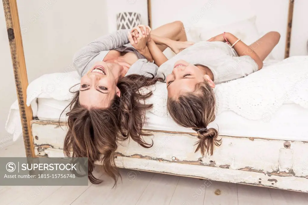 Mother and daughter lying together on bed having fun