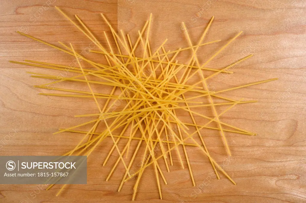 Raw spaghetti lying on wooden table