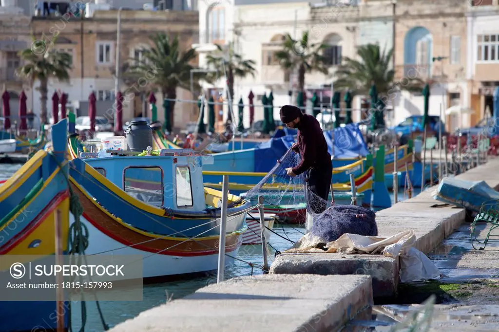 Malta, Marsaxlokk, Fisherman repairing fishing net