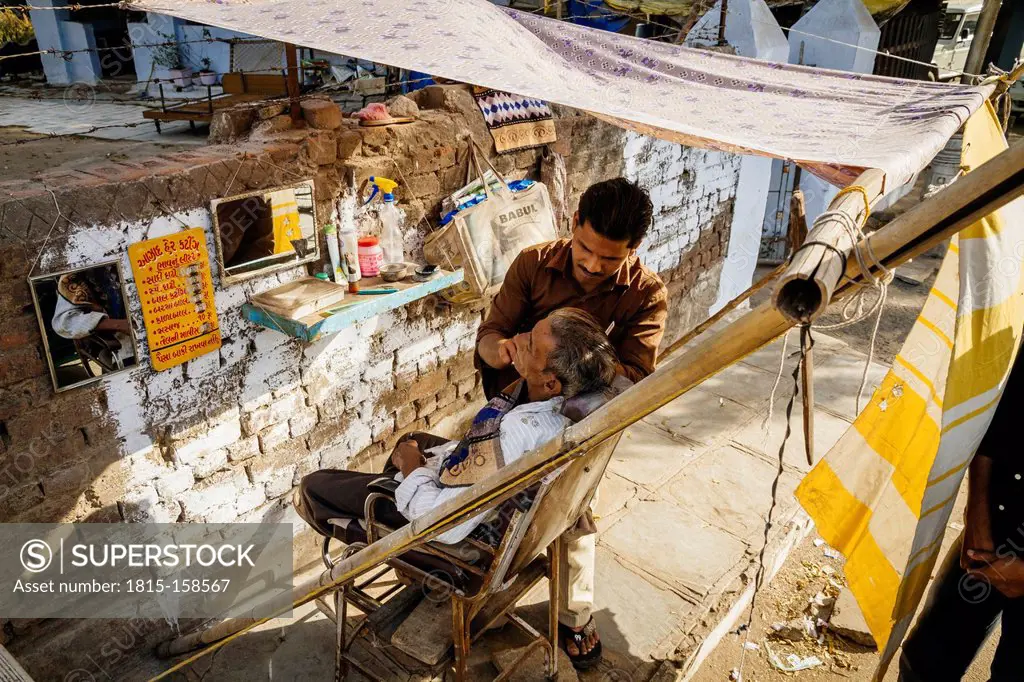 India, Ahmedabad, Street barber shaving customer