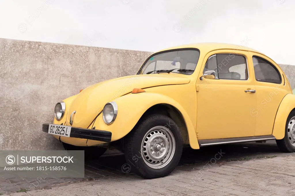 Spain, Lanzarote, Teguise, yellow VW beetle parking in front of a wall