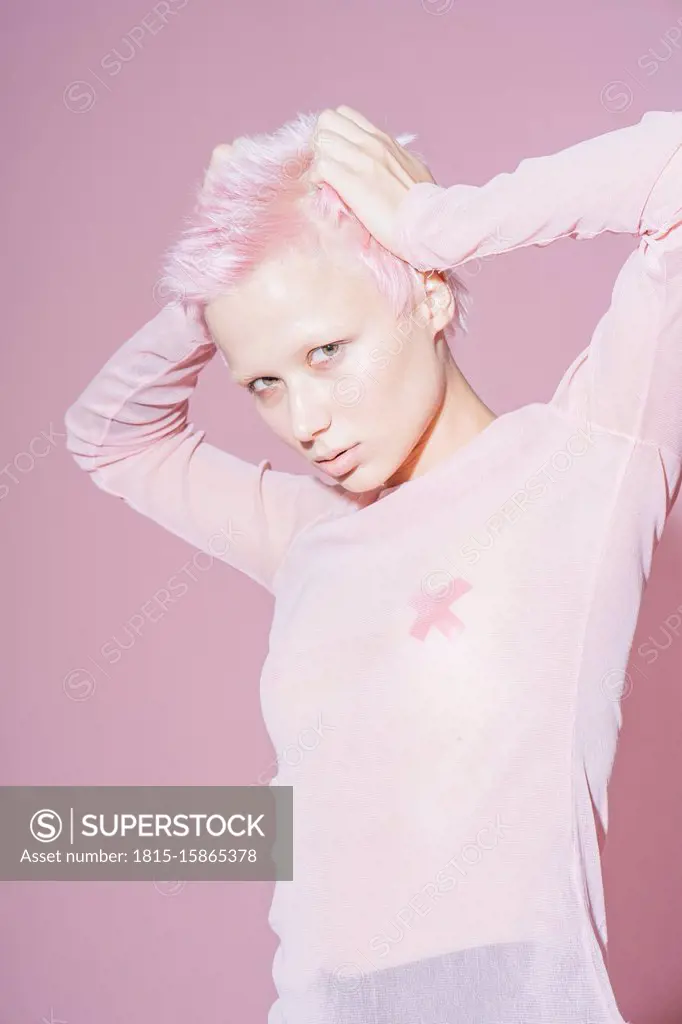 Portrait of young woman with short pink hair wearing pink top in front of pink background
