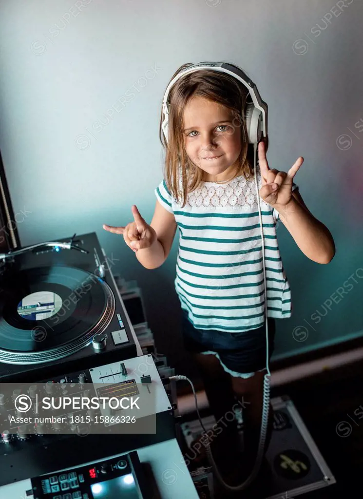 Portrait of little DJane with headphones showing Rock And Roll Sign