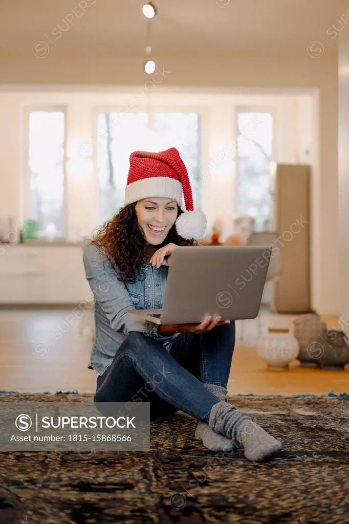 Woman with Santa hat looking for presents online, using laptop