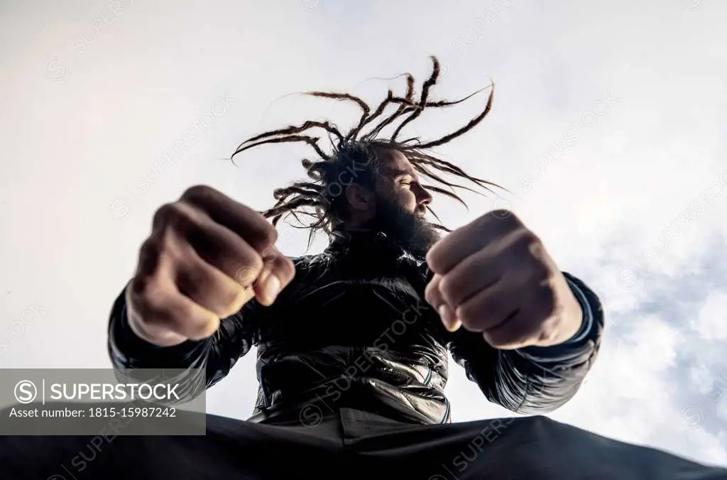 Bearded man with dreadlocks clenching fists