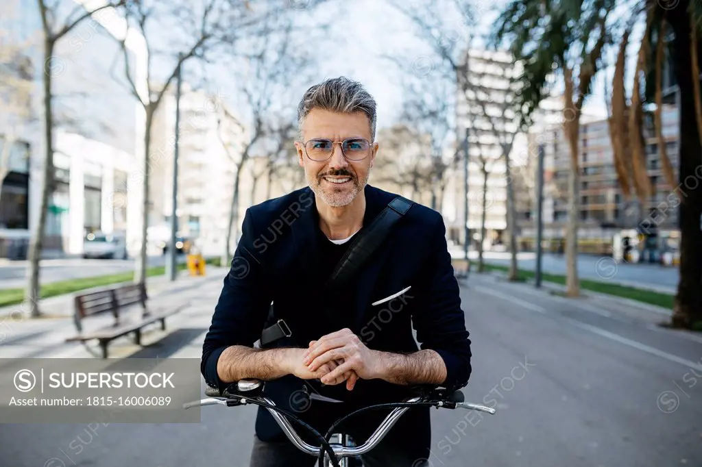 Portrait of a gray-haired businessman with bicycle in the city