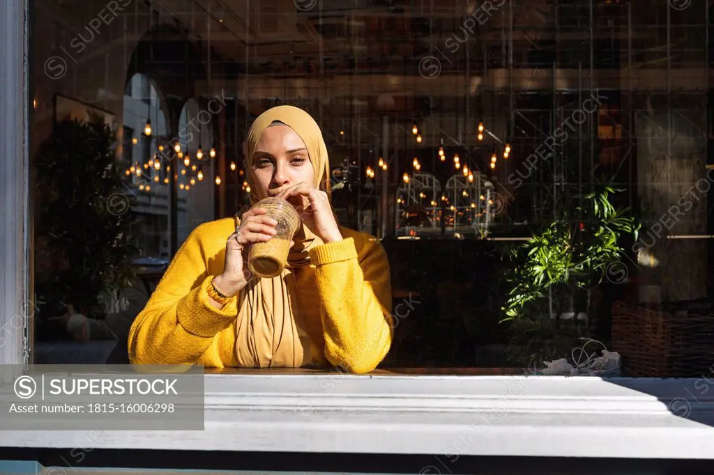 Portrait of young woman drinking smoothie in a cafe