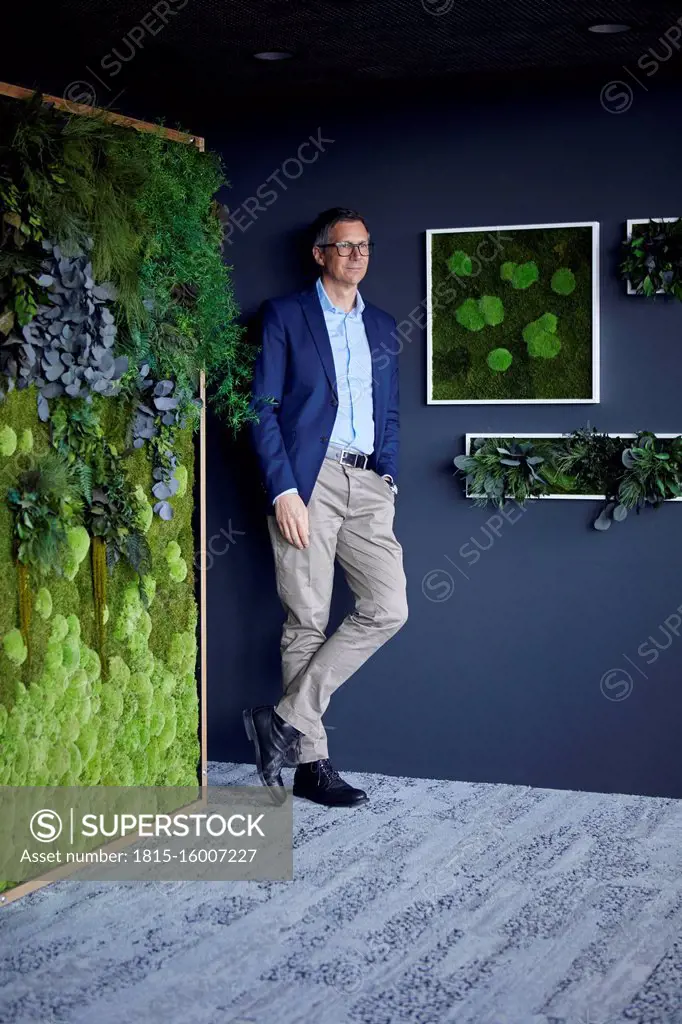 Businessman standing at the wall in green office