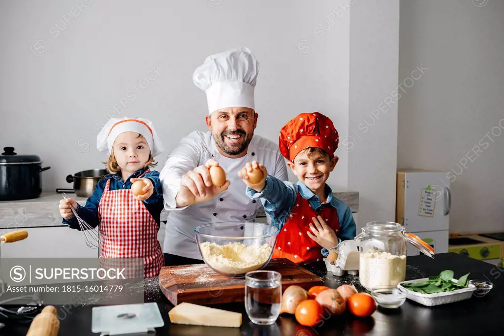 Portrait of father with two kids preparing dough in kitchen at home