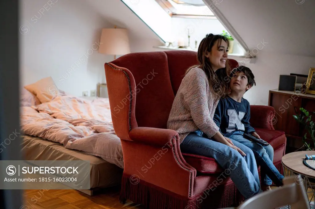 Mother and little son sitting together on couch watching television