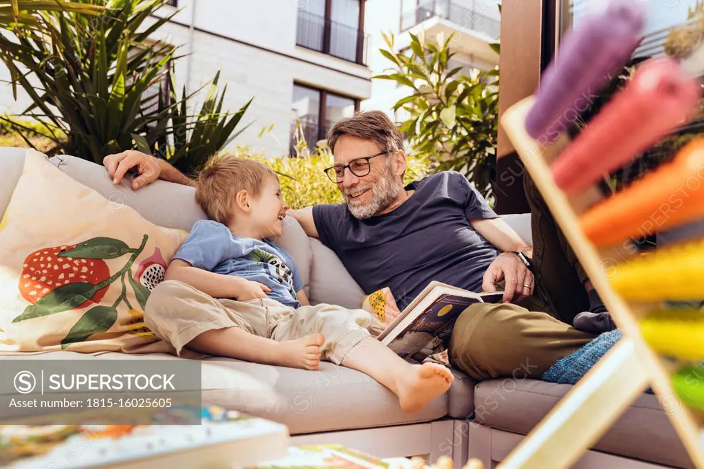Father and son reading a book on their terrace