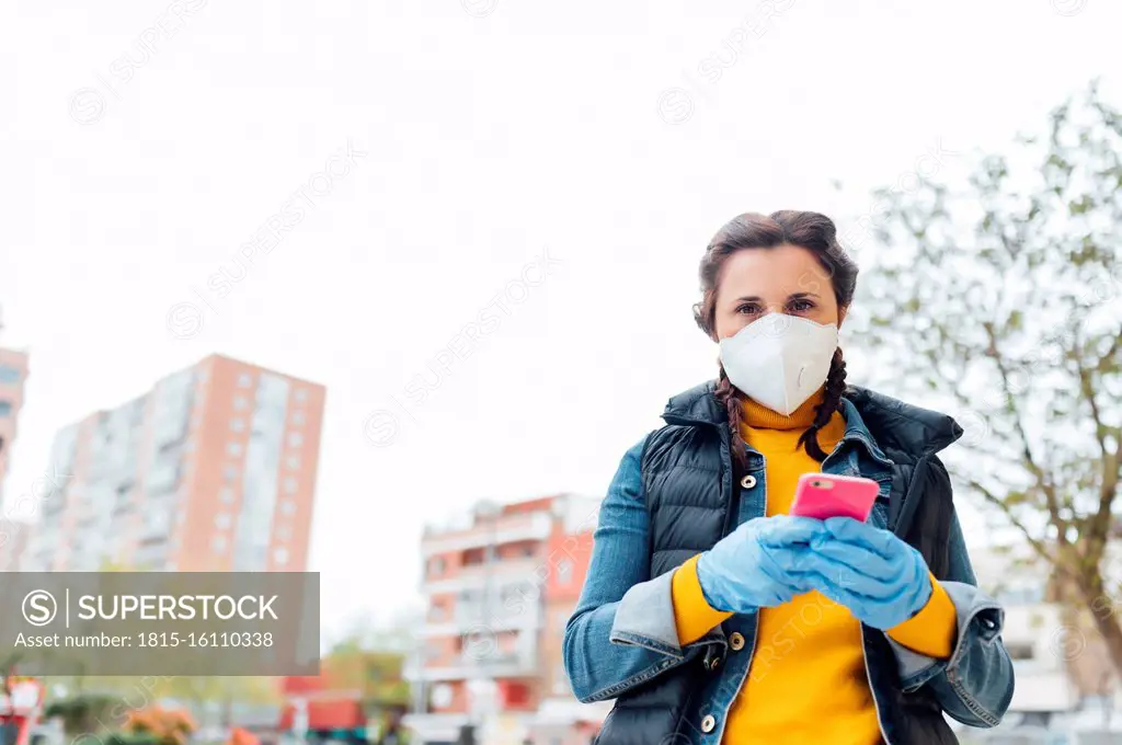 Woman wearing protective mask and using smartphone in the city