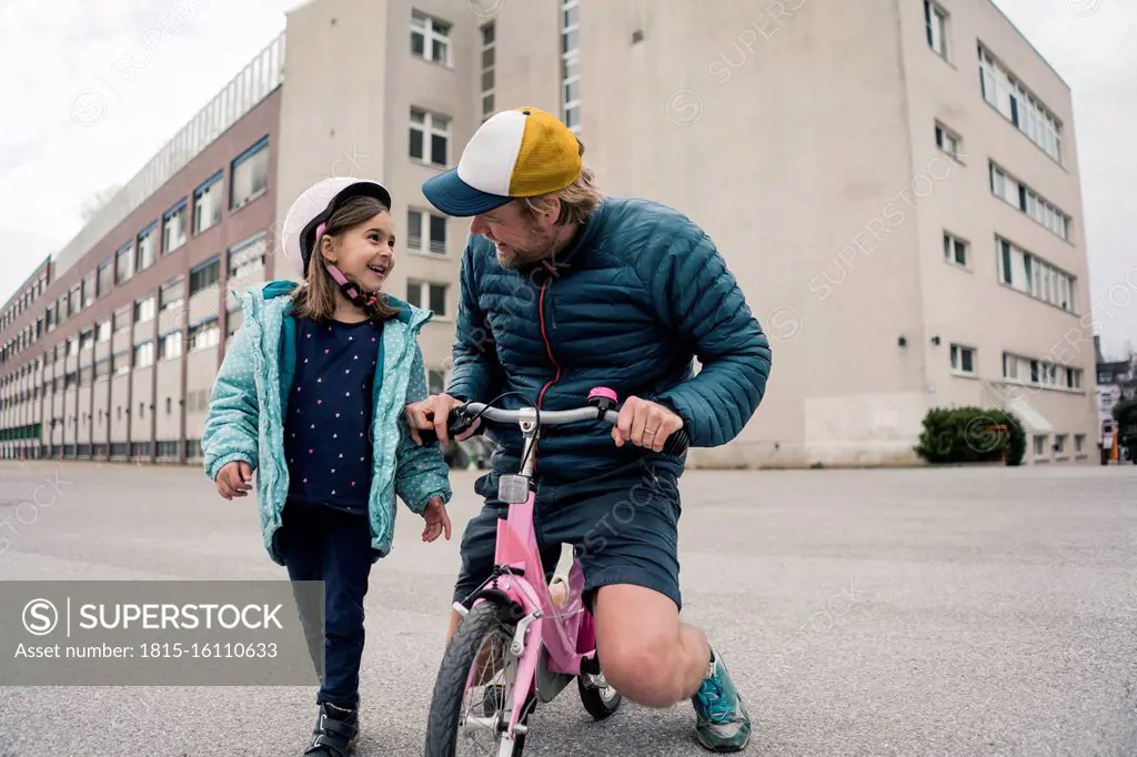 Happy father with daughter on her bicycle