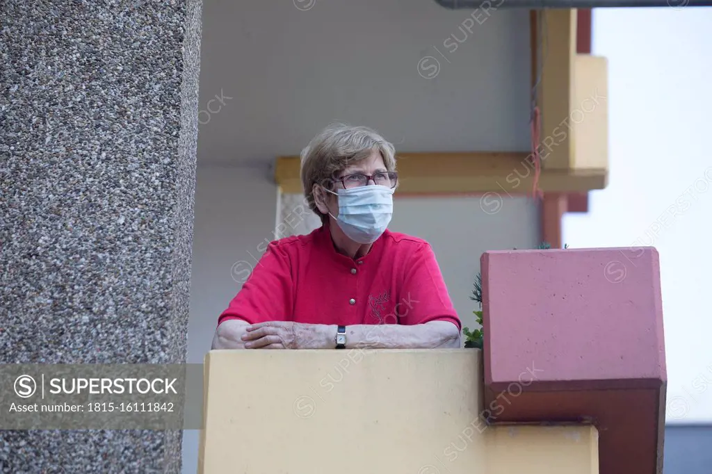Senior woman wearing mask on balcony, retirement home