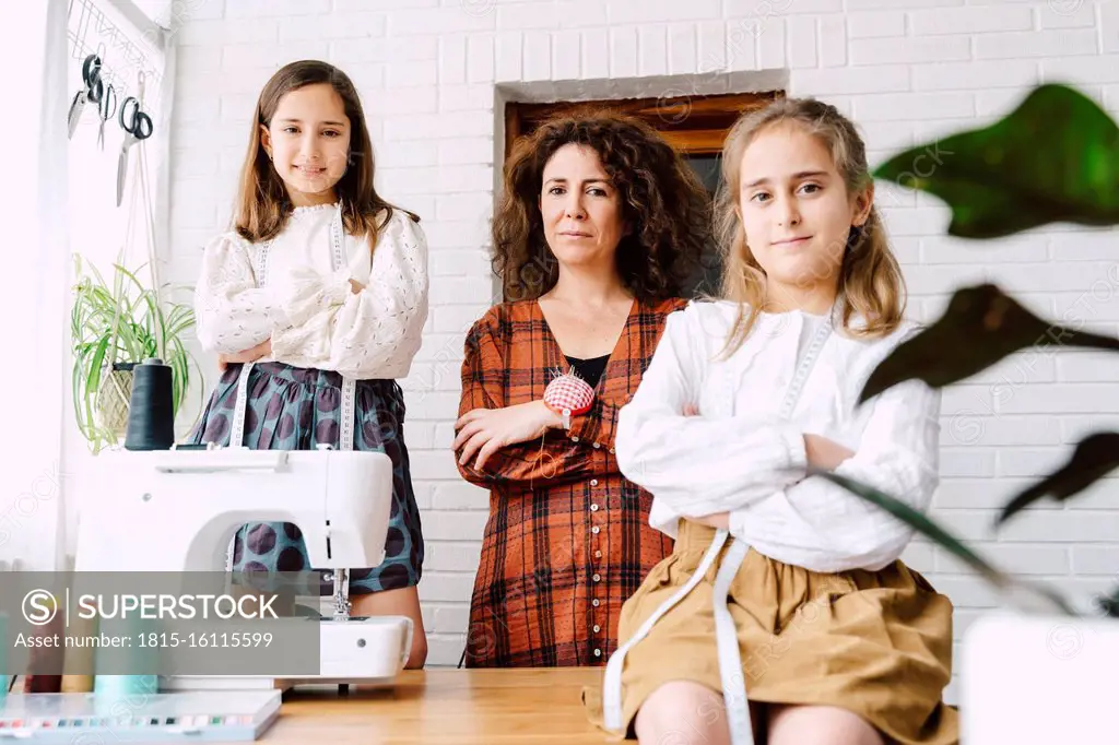 Portrait of mother and two daughters with sewing machine at home