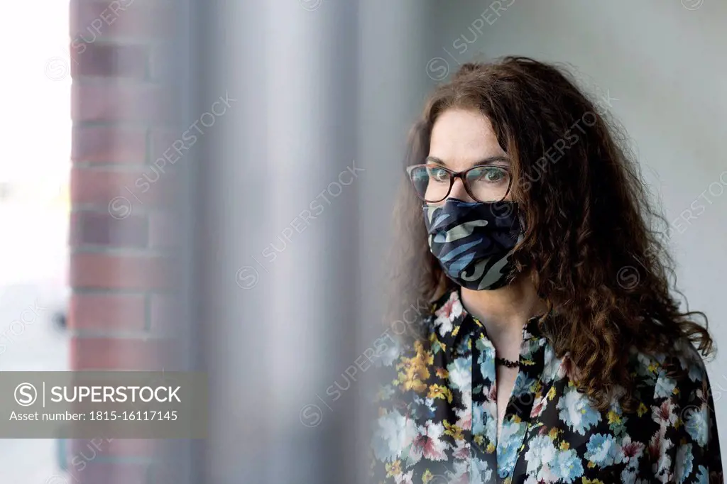 Woman wearing protective mask at window glass