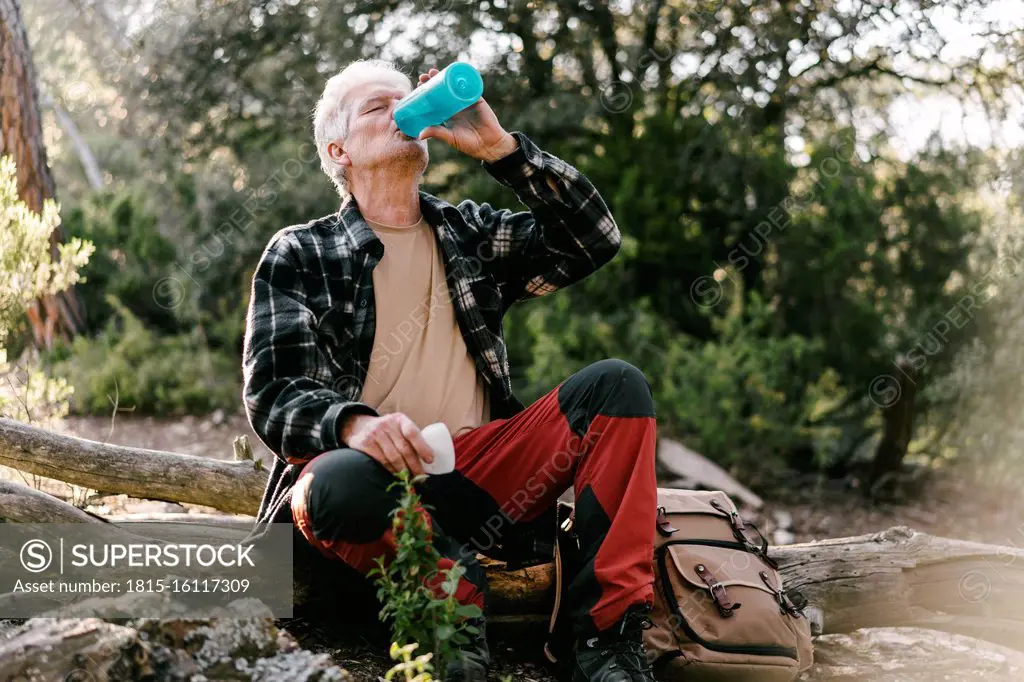 Hiker with backpack having a break drinking water from bottle